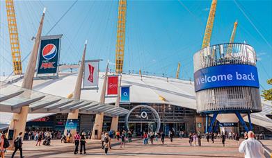 The O2 dome in white covering with 5 yellow stands visible and large glass door entrance