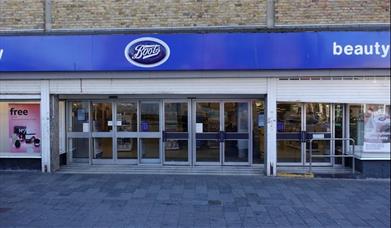 Outside Boots in Eltham, showing a blue and white styled shop with a glass door entrance.