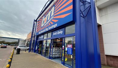 Outside B&M in Charlton. A large blue and orange building with automatic doors, located next to a car park.