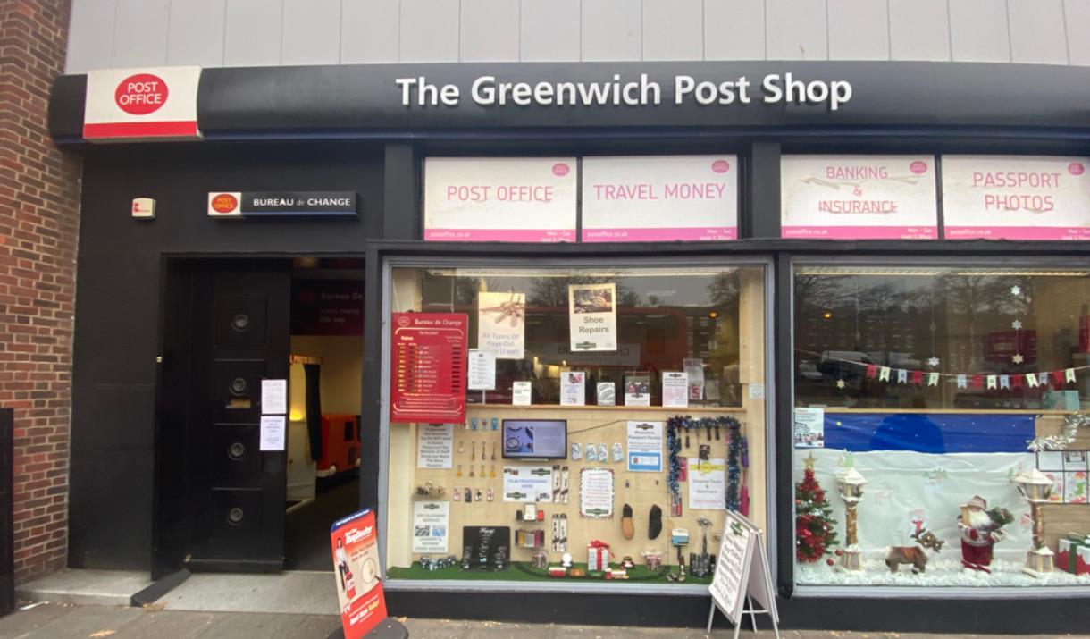 Outside Greenwich Post Office. A black, red and white shopfront with a window showing envelopes and other stationary.