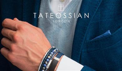 Tateossian London. A man wearing a blue blazer and blue bracelets. A white logo saying Tateossian London sits at the top of the image.