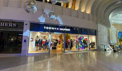 Outside Tommy Hilfiger at The O2. A navy shop front with windows showing a stunning inside area.