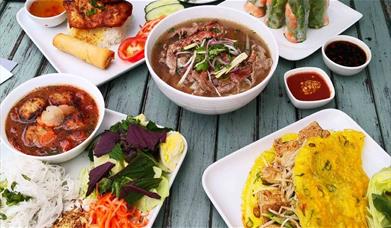 A table set with variety of Viet Baguette's meals including appetisers Summer Rolls, Pancake and Pho Chiri and Com Dac Biet.