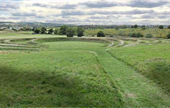 The earthwork sculpture at Theydon Bois seen from the top of the hill with M11 on the left and new woodland beyond the sculpture.