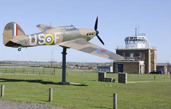 The Hurricane "Gate-Guardian" at North Weald Airfield with control tower in the background.