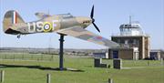 The Hurricane "Gate-Guardian" at North Weald Airfield with control tower in the background.