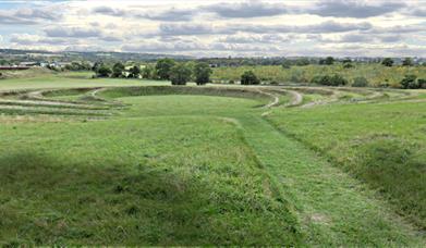 The earthwork sculpture at Theydon Bois seen from the top of the hill with M11 on the left and new woodland beyond the sculpture.