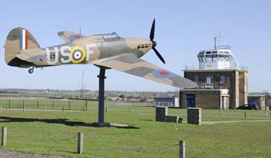 The Hurricane "Gate-Guardian" at North Weald Airfield with control tower in the background.