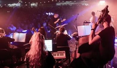 A classical orchestra and conductor under disco lights