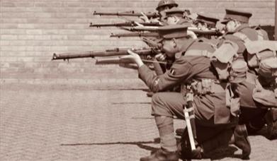 10th Essex Battalion WWI Re-enactment Group dressed as World War 1 soldiers, crouching down to fire their rifles in a line