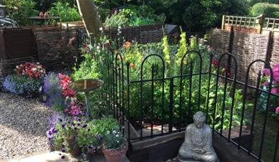 Small decorative cottage garden with pots and statues