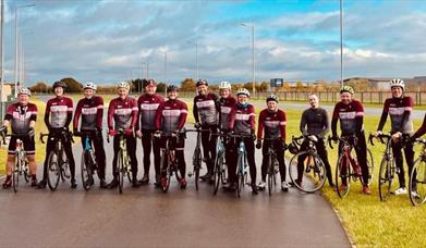 A group of cyclists in a line, wearing club shirts.