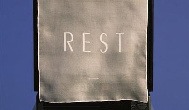 a cloth with the word 'REST' printed onto it covers a monitor or screen