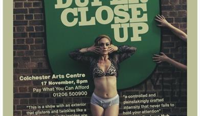 A woman in bra and pants poses for the camera in front of a brick wall. Text advertises the show.