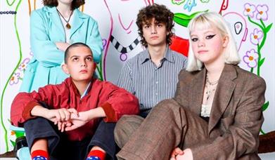 The four members of Anorak Patch pose in front of a mural.