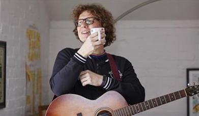 Kevin Pearce with a cup of tea and acoustic guitar