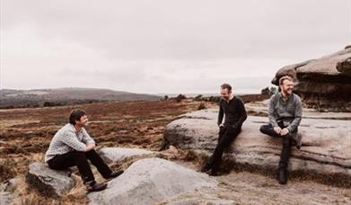 Three men sitting on rocks on moorland