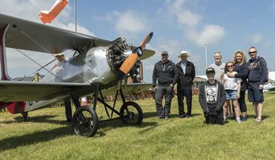 Family standing next to a vintage aircraft