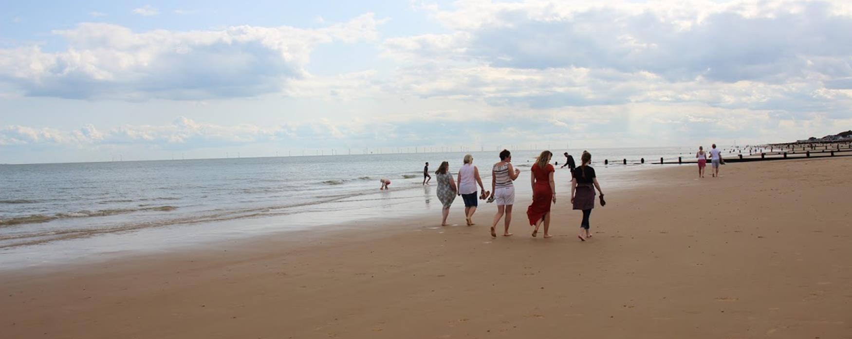 A group of people walking along Frinton-On-Sea beach
