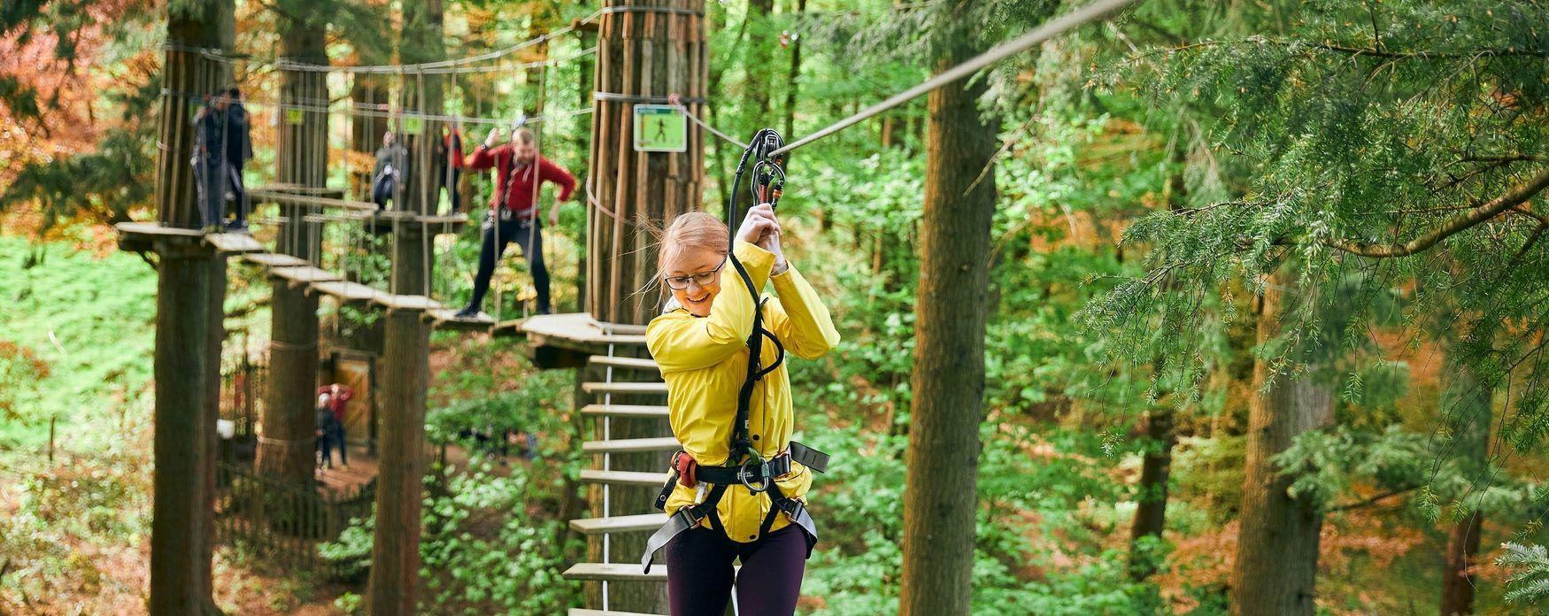 Girl in yellow jacket on high wire at Go Ape