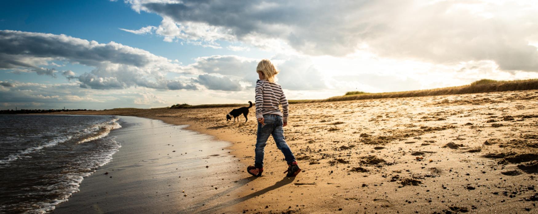 A child walking along Jaywick beach in the sunshine