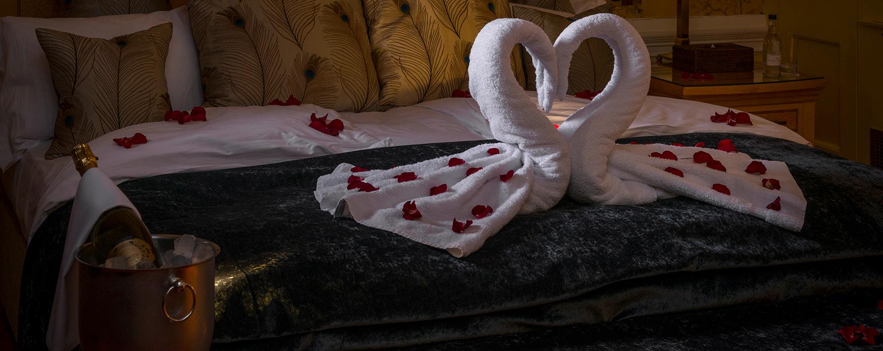 romantic bed laid out with petals and swan towels arrangement
