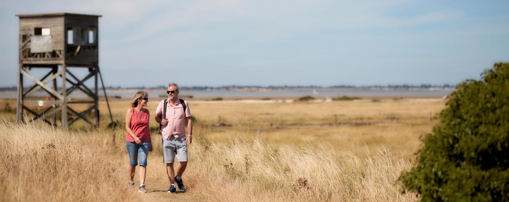 Two people walking along the Saltmarsh Coastal Trail at Bradwell on Sea