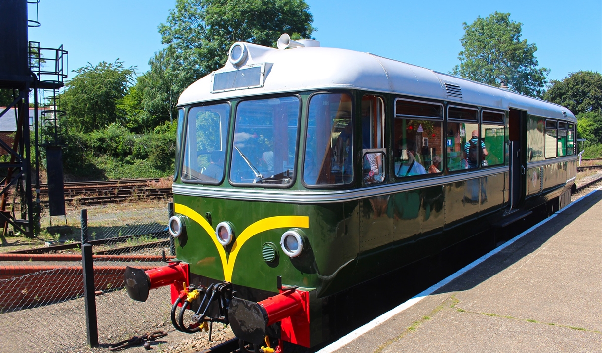 A small green Waggon und Maschinenbau Railbus E79963 sits by the platform