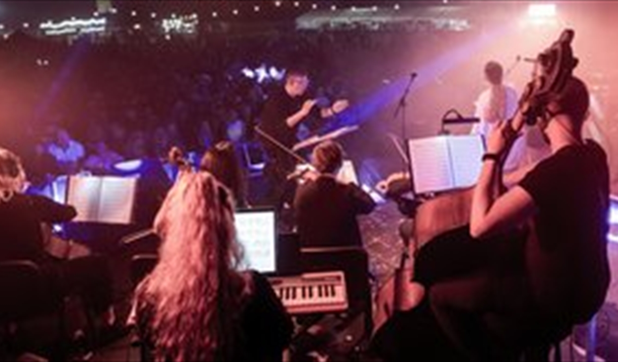 A classical orchestra and conductor under disco lights