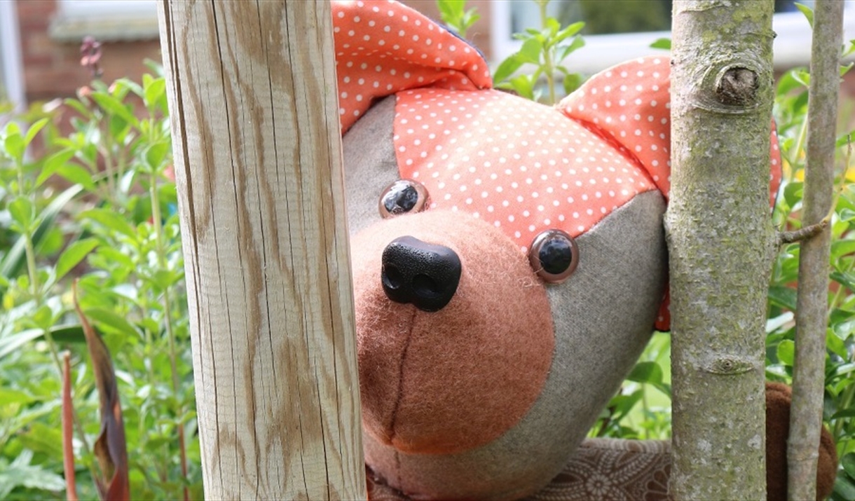 A teddy bear looks through some tree branches