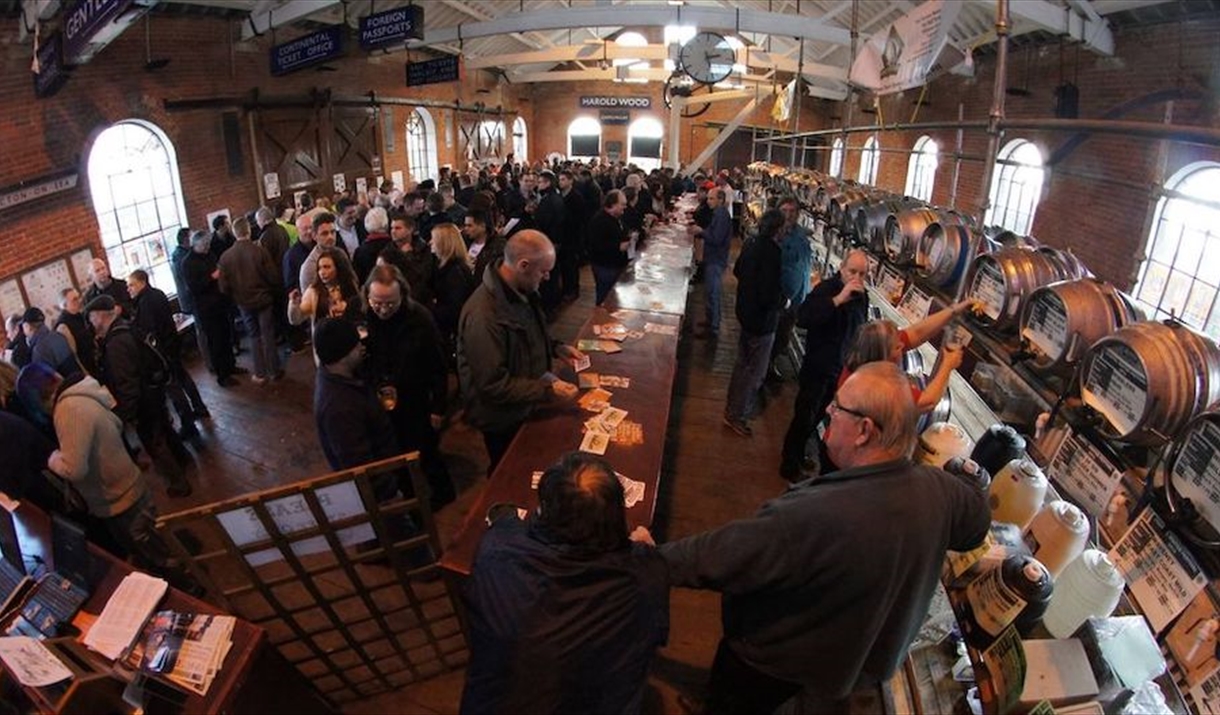 A crowded goods shed at the East Anglian Railway Museum, lined with kegs of beer.