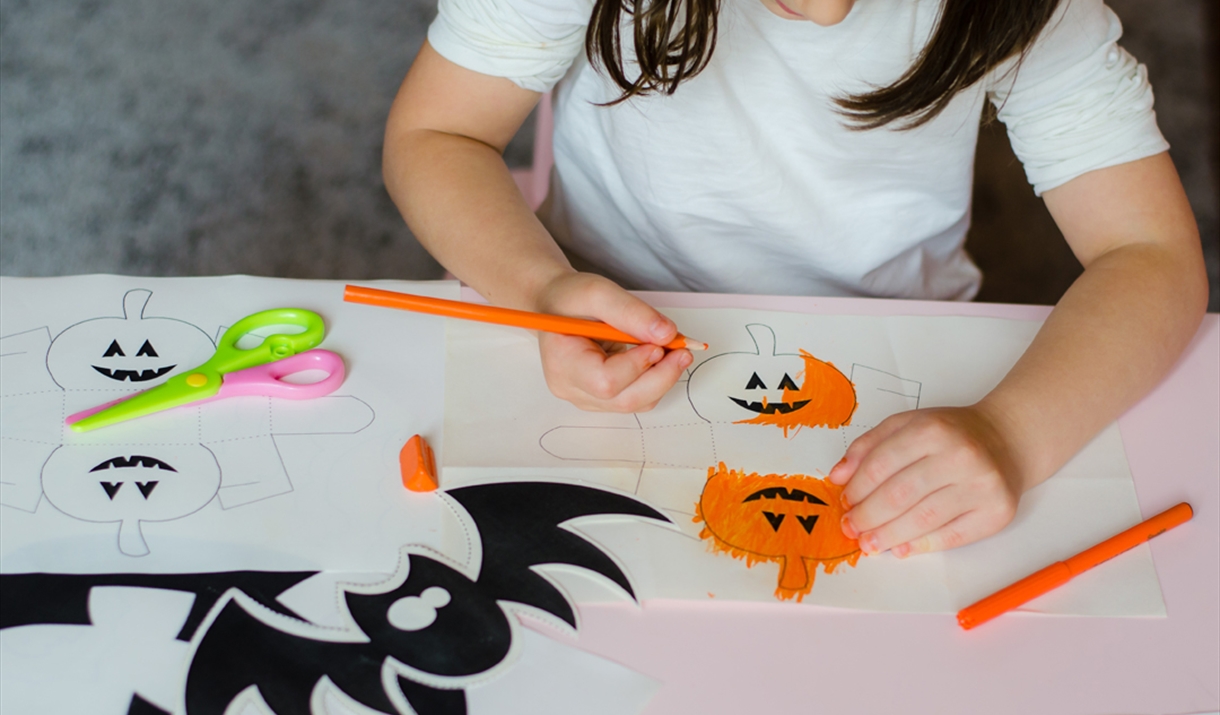 A child colours in pumpkins