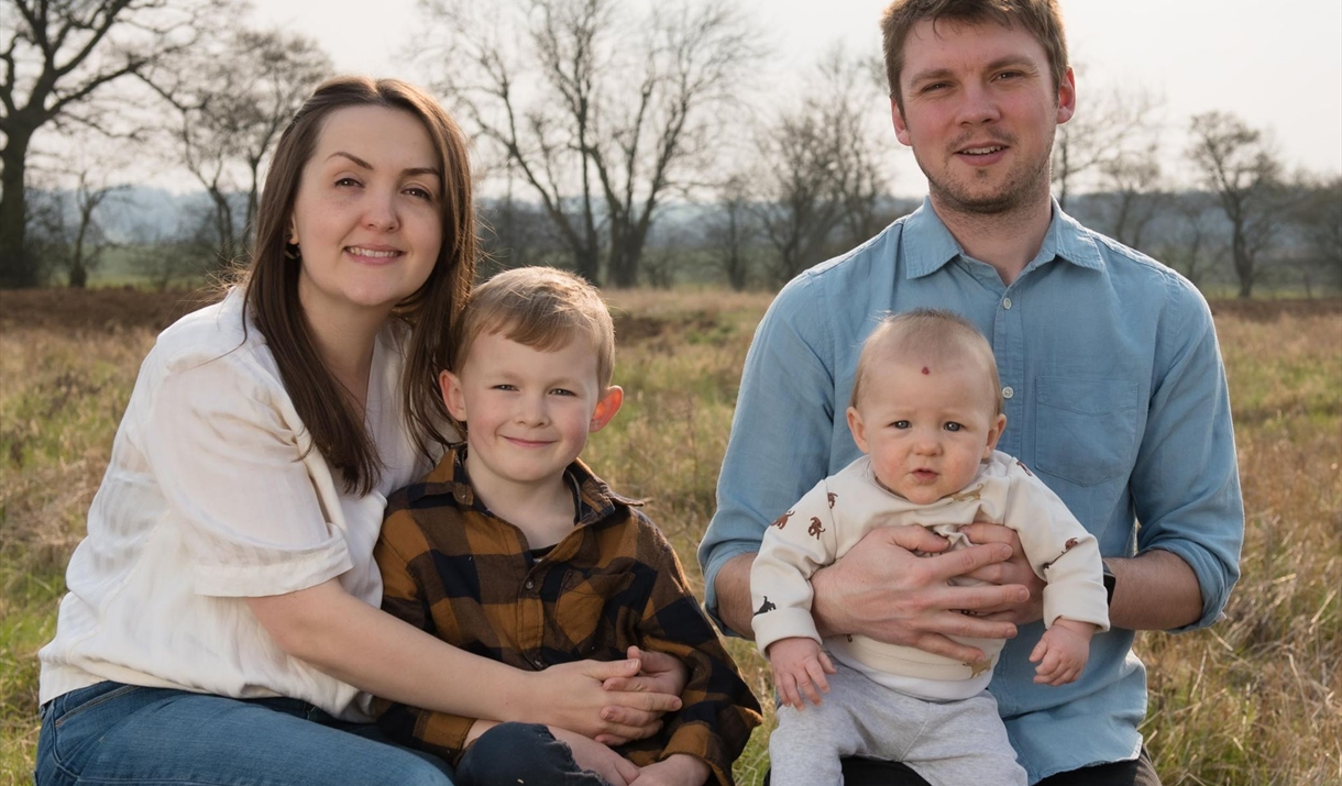 Family posing for photograph on wooden log in countryside