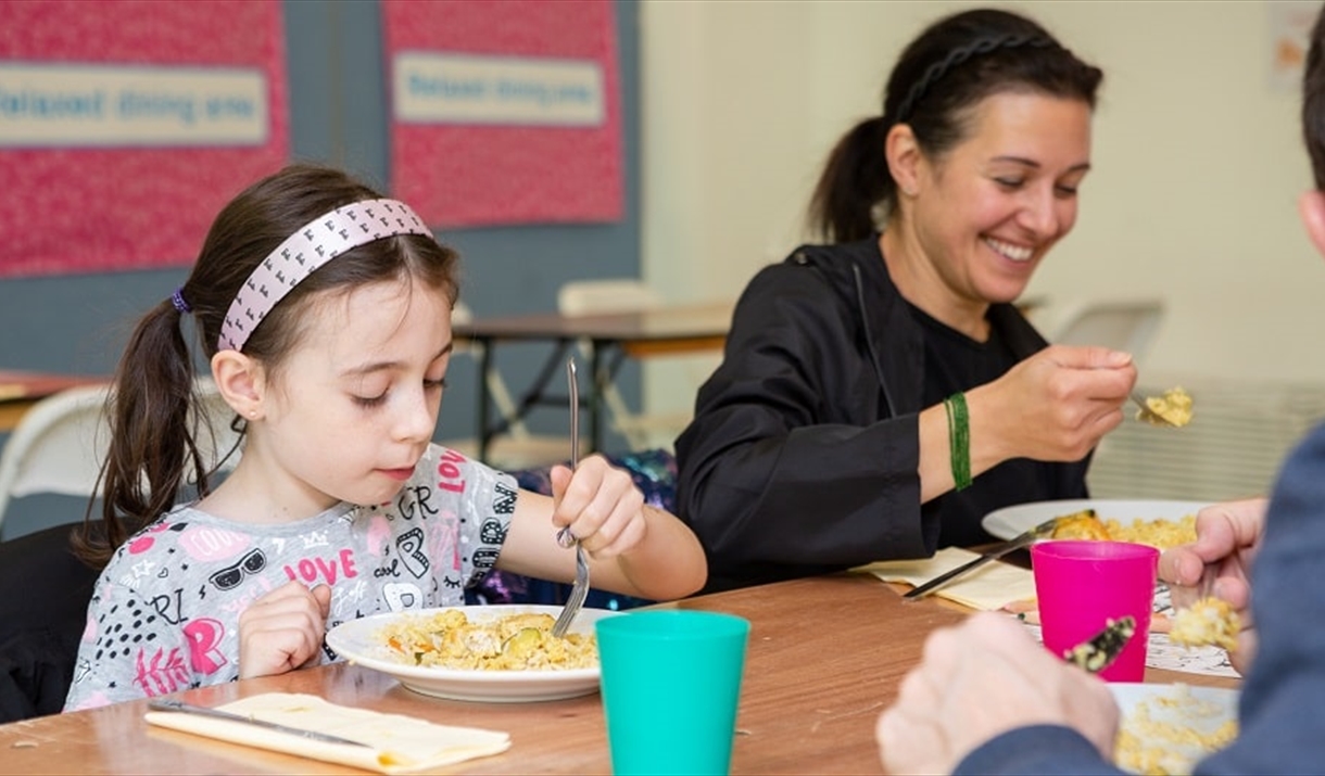 An adult woman and child eating a plate of food and smiling.