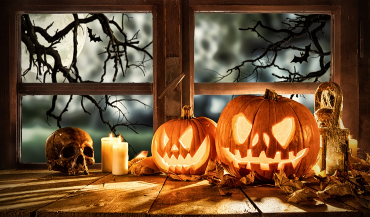 Carved pumpkins, candles and skull on windowsill
