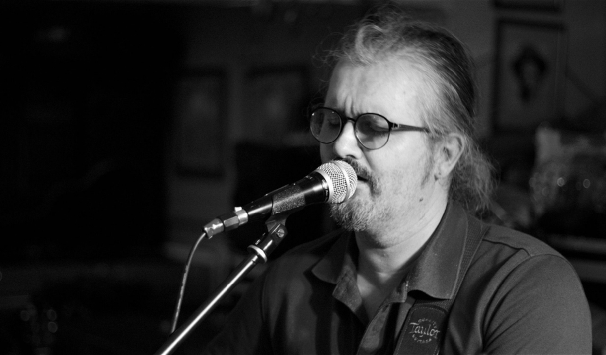 Folk singer Dan Fraser singing, moody black and white photo