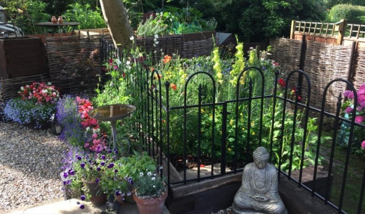 Small decorative cottage garden with pots and statues