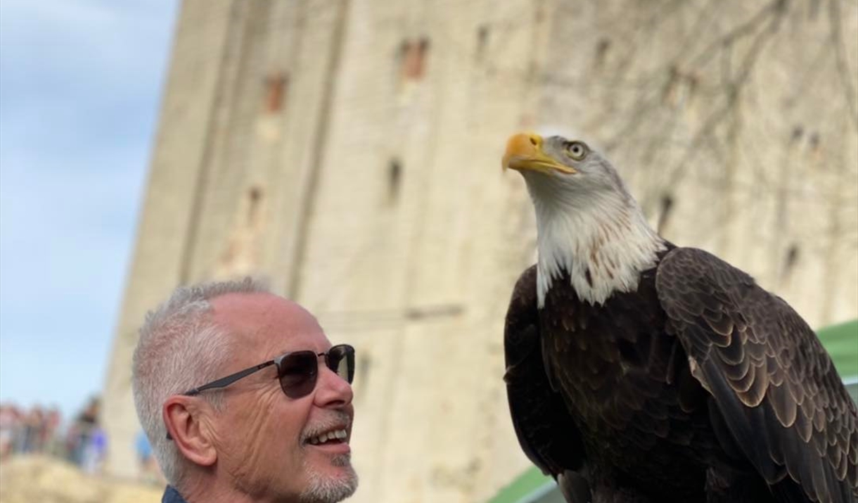 Nik Kershaw holding a bird of prey with Hedingham Castle in the background