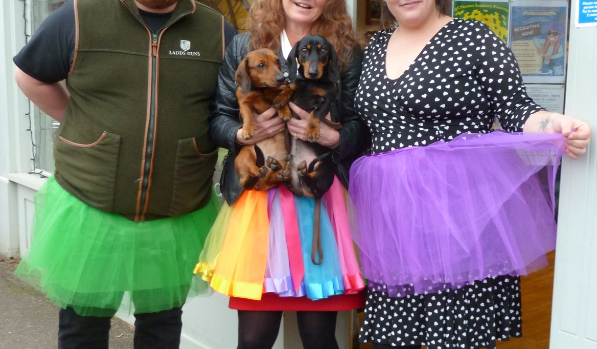 3 people wearing TuTu's , green, rainbow colour and purple