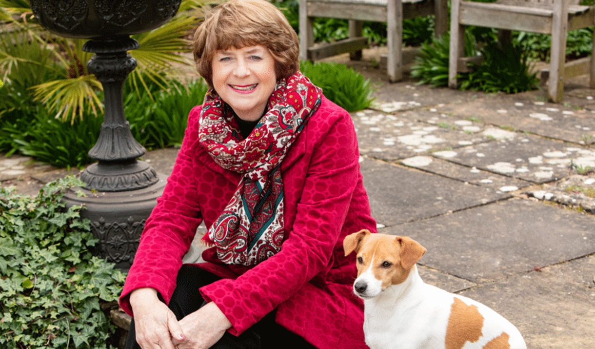 Pam Ayres sitting with her dog in a garden