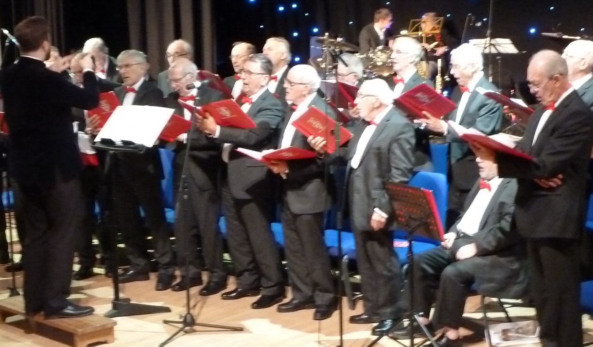 Male choirsters holding red song books