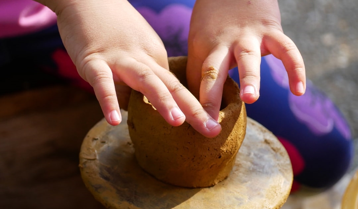 a child's hands making a clay pot