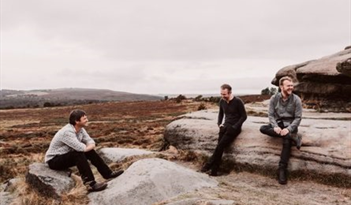 Three men sitting on rocks on moorland