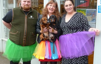 3 people wearing TuTu's , green, rainbow colour and purple