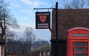 The Castle Park Ranger Station, with its sign containing the colchester coat of arms, with a red telephone box outside