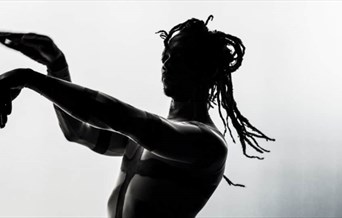 A half-silhouetted dancer gestures with his hands