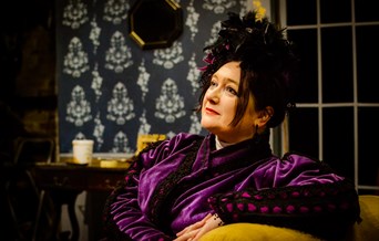 A victorian woman sits on a chair