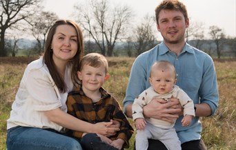 Family posing for photograph on wooden log in countryside