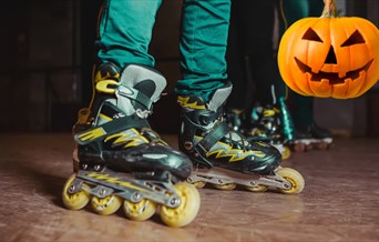 Person with black and yellow roller skates on and a carved pumpkin in the background