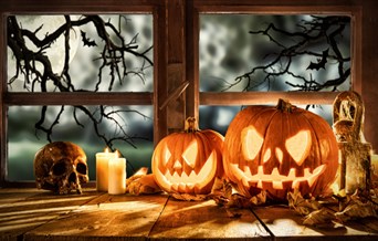 Carved pumpkins, candles and skull on windowsill